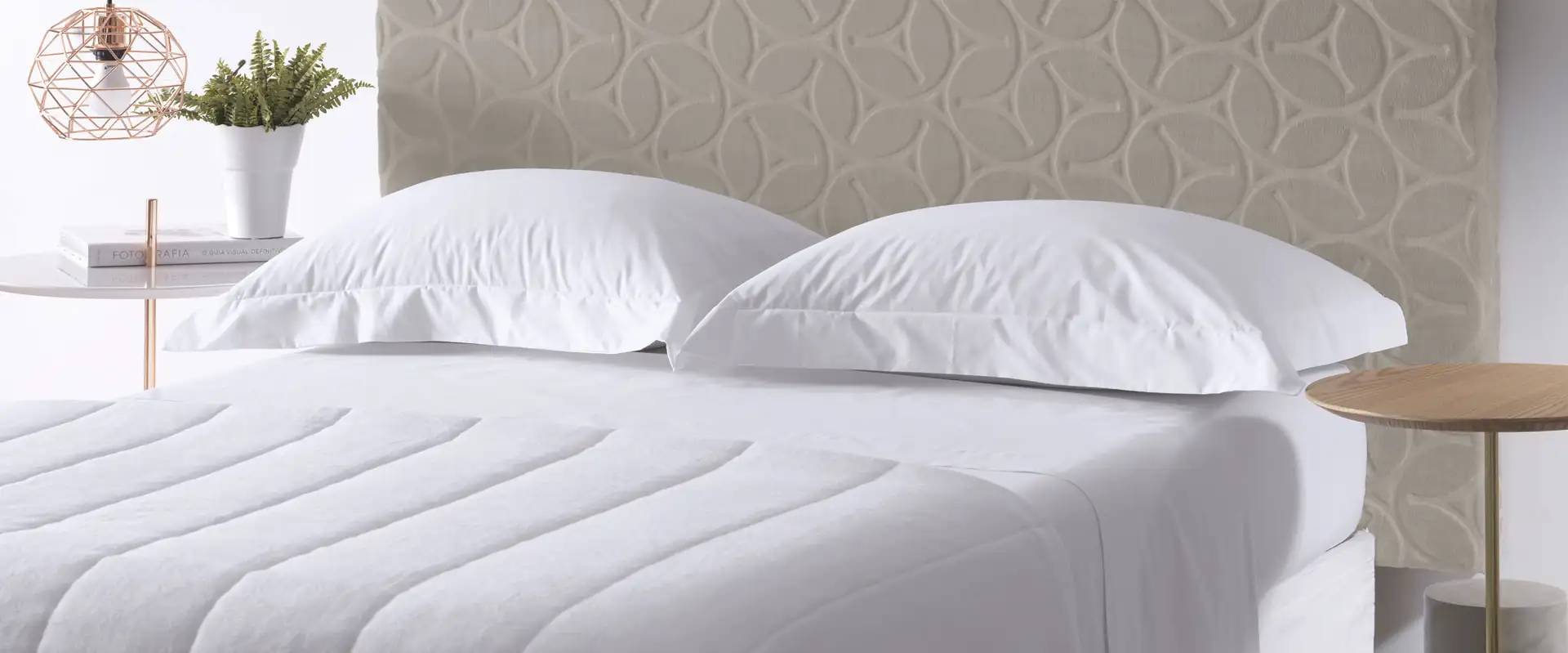 Cama com cabeceira estofada e roupa de cama branca